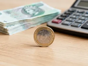 Profesjonalne biurko z kalkulatorem i monetami, symbolizujące planowanie budżetu oraz obliczenia finansowe.
